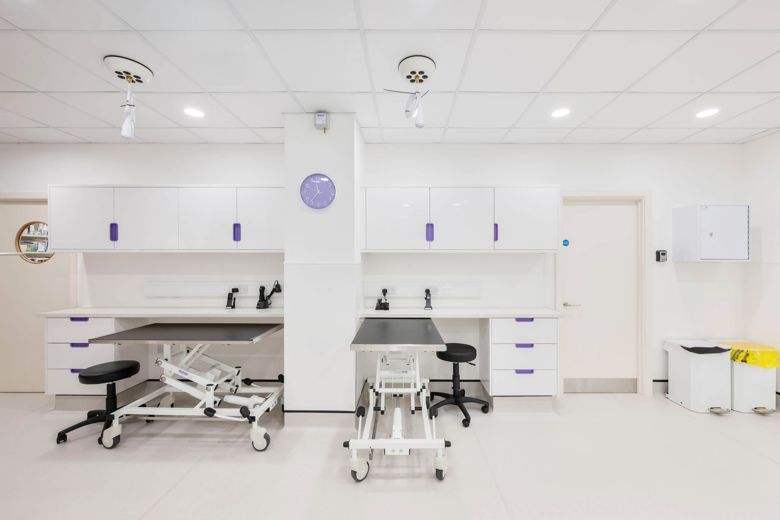 Bright and modern medical examination room with white surfaces and purple accents.