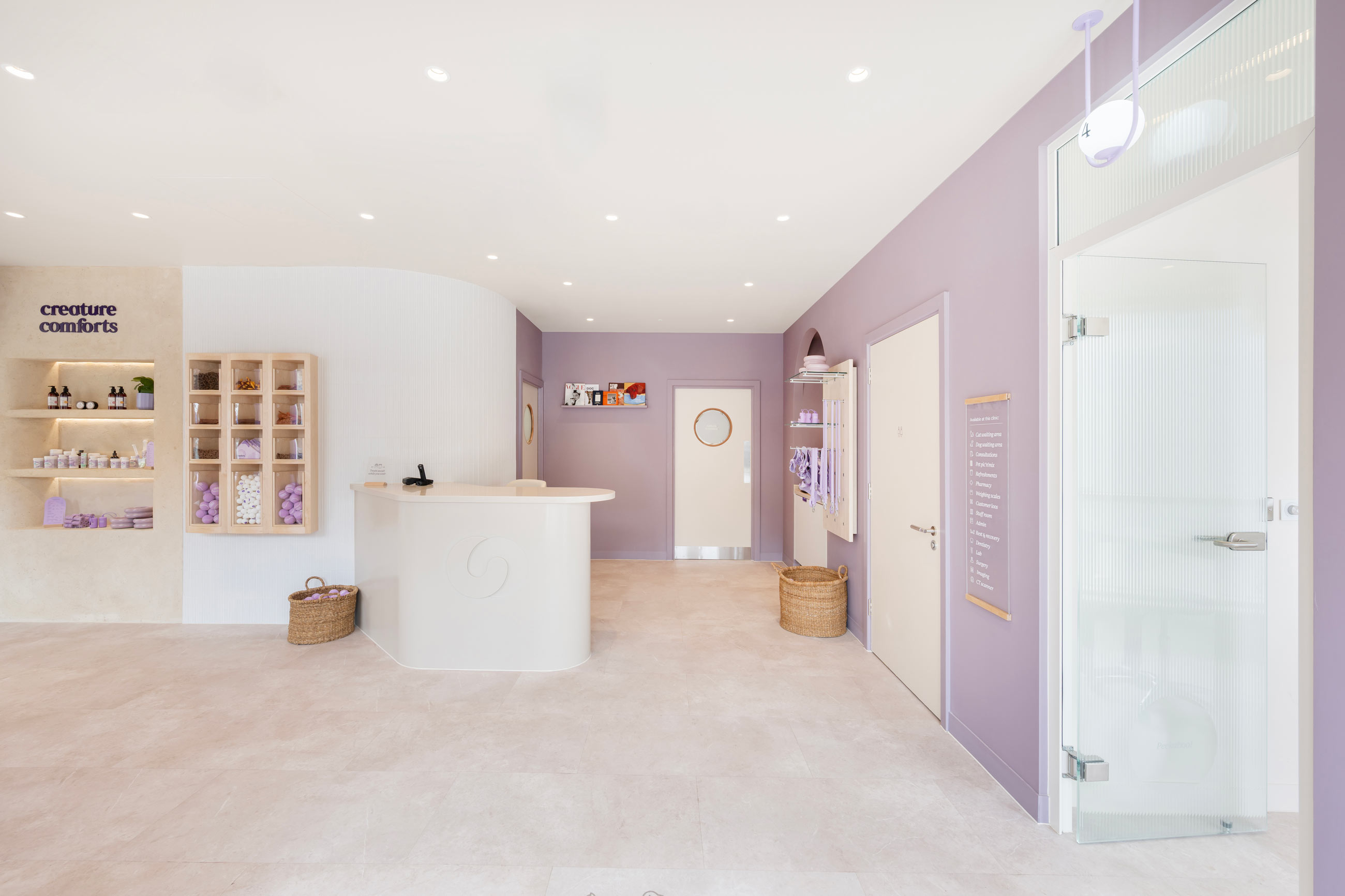 A stylish, modern reception area in soft lavender tones featuring a circular desk, product display, and cozy decor elements.